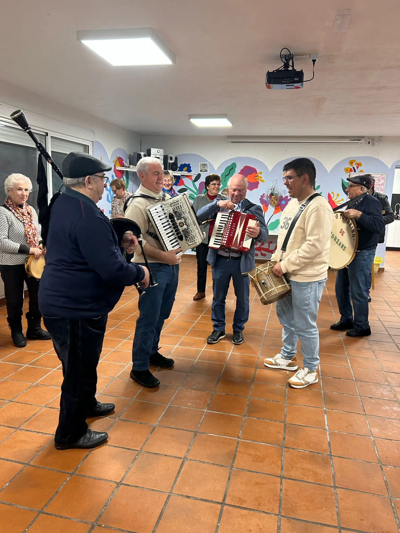 Village musicians with bagpipe, two accordions, tamboril and bass drum playing indoors at the Casa do Pobo