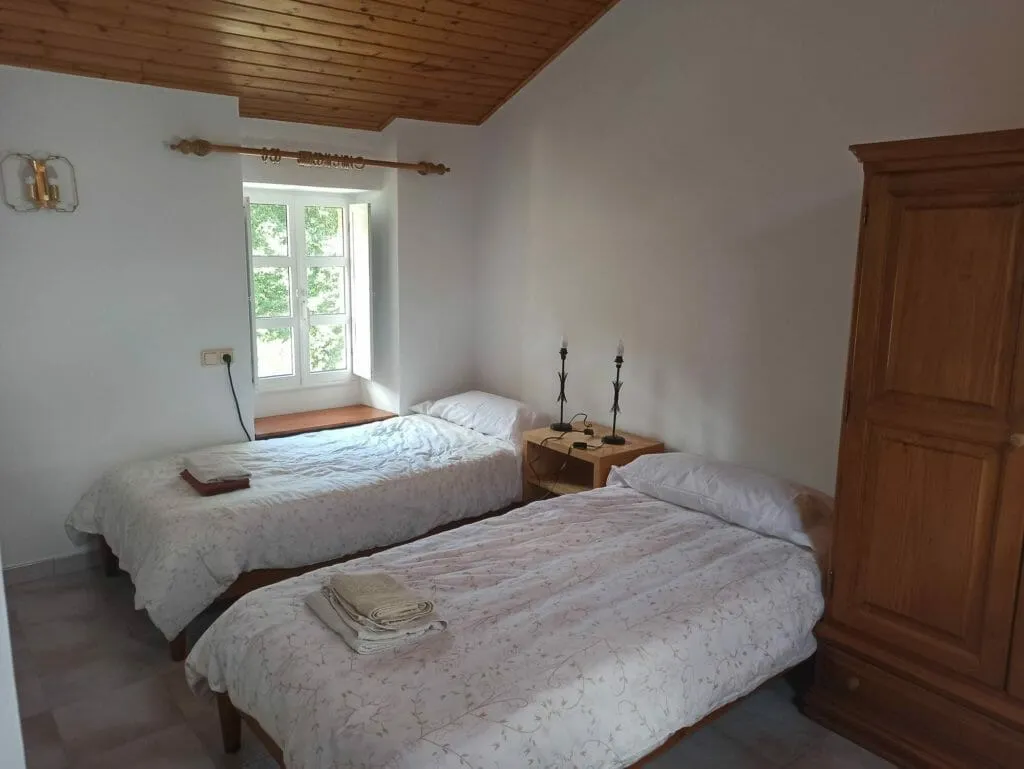 Room 104 before its redesign: two single beds with floral bedspreads, a wooden wardrobe and a paneled wooden ceiling