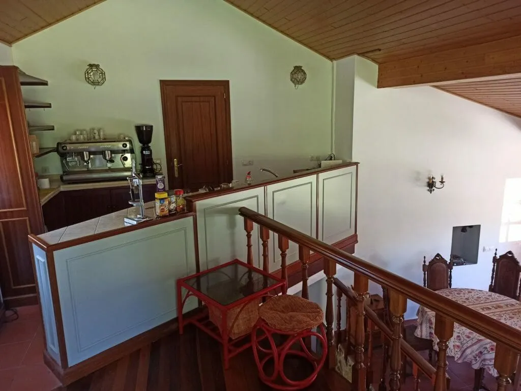 The cafe before its redesign: pale green paneling, dark wood trim and a red rattan table beside the espresso machine