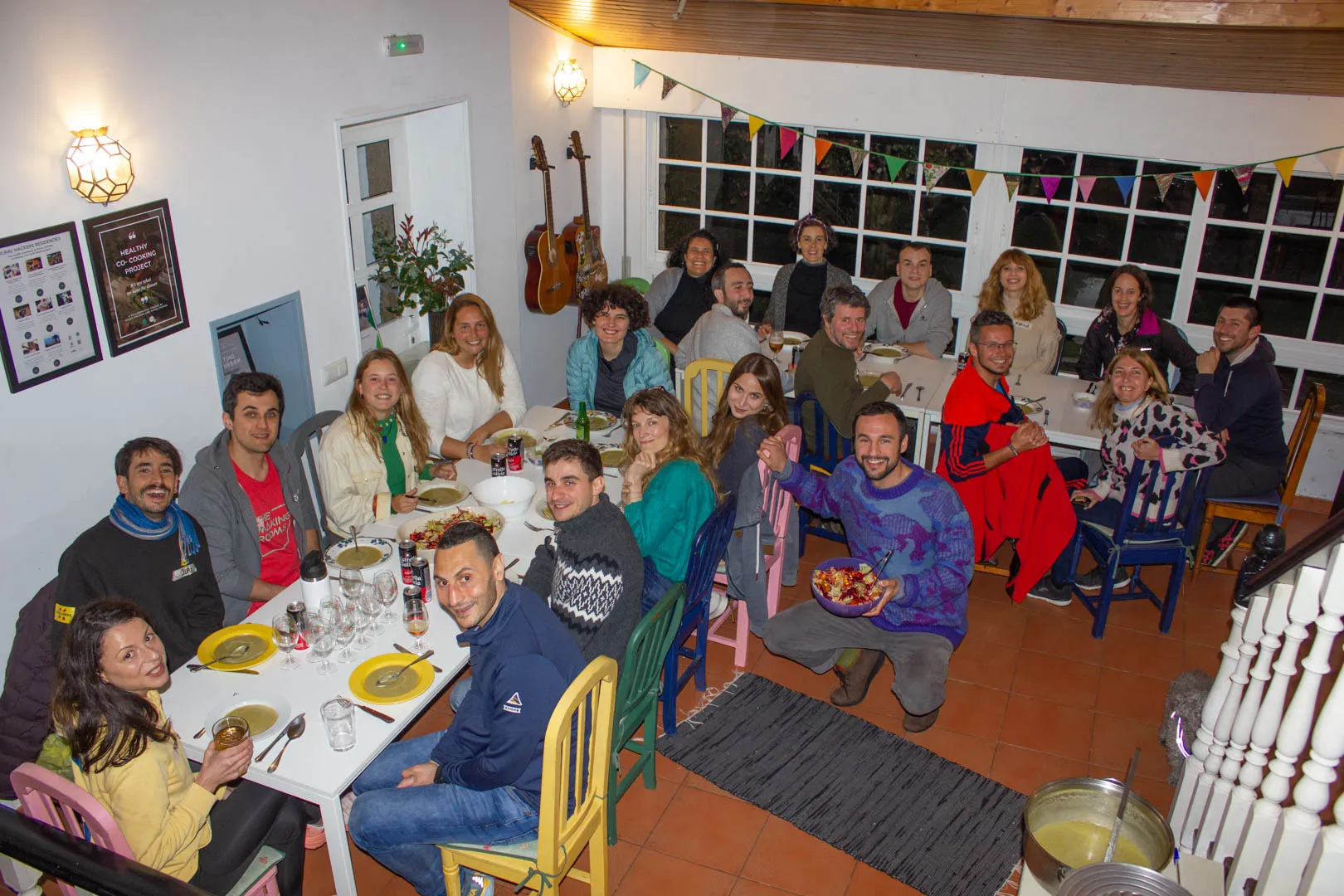 Around twenty people gathered at long tables for dinner in a bright room hung with bunting, bowls of soup in front of them