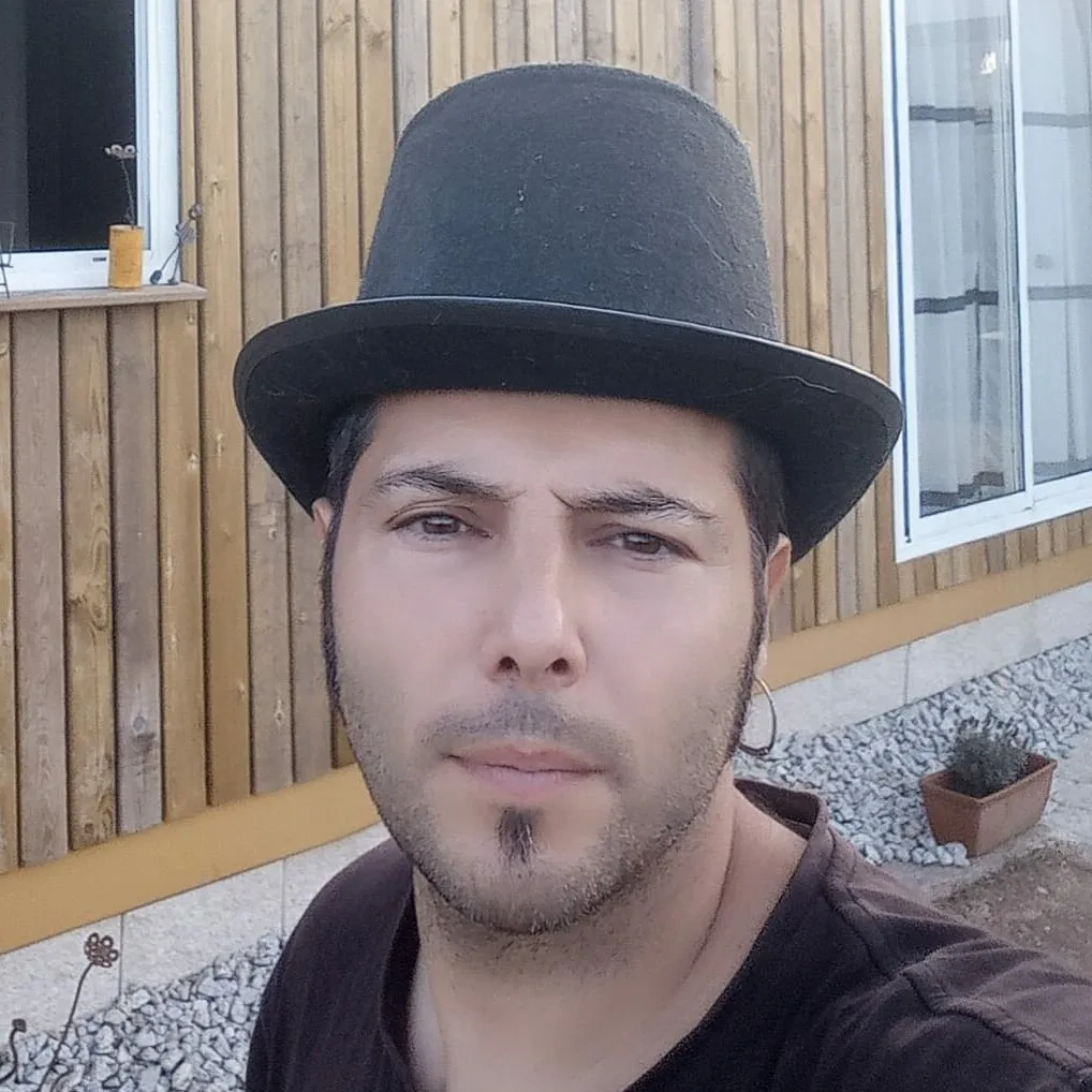 Charlie, in a black top hat, in front of the timber-clad wall of the house